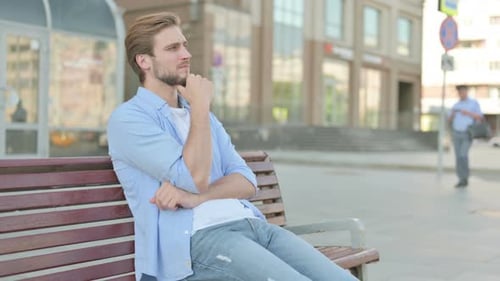 Young Man Ponders on City Bench