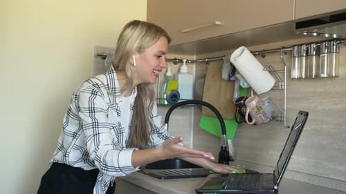 Woman Cleaning Kitchen While Talking on Laptop