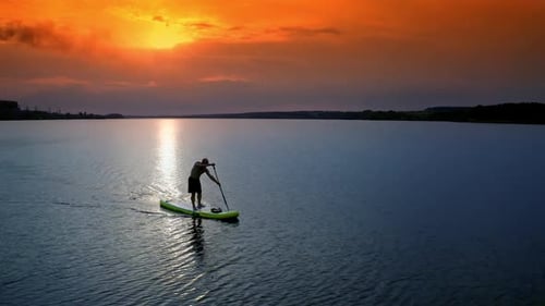 Person Paddleboarding on Lake at Golden Sunset