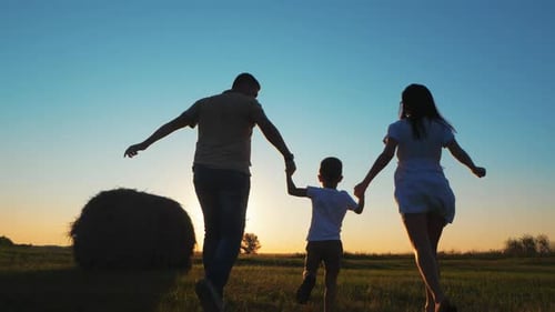 Family Silhouette Running at Sunset in Grassy Field