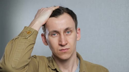 Young Adult Styling Hair in Front of Gray Wall