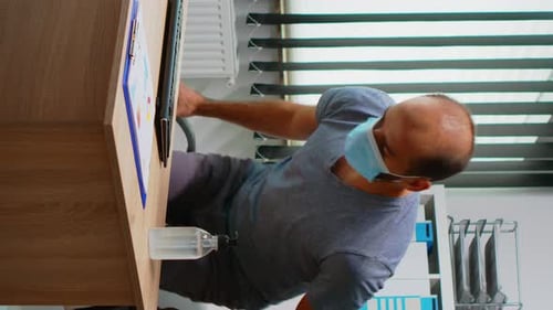 Man Sanitizes Hands at Office Desk with Monitor