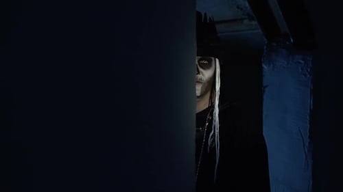 Sinister Man with Halloween Skeleton Makeup Slowly Appears From Dark Corner with Frightening Smile