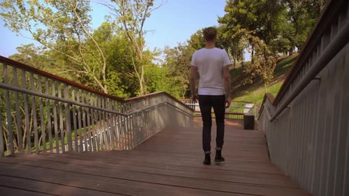Man Walking Down Stairs in Urban Park on Sunny Day