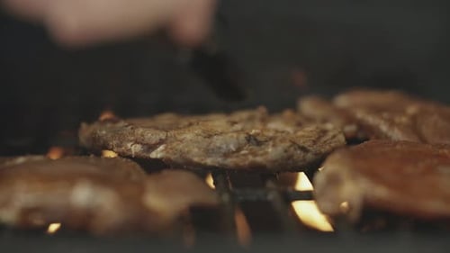 Meat Cooking on Grill with Flames and Tongs