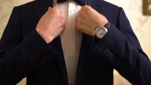 Groom puts on a black suit. A man buttoning his jacket, close-up.