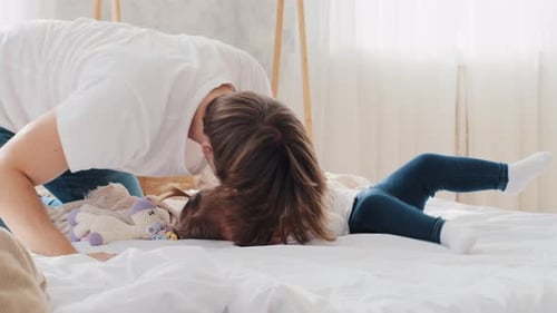 Loving Father Playfully Interacts with Child on Bed