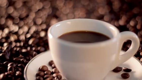 Hot steaming cup of coffee in a land of coffee beans. Tasty delciious drink beverage caffeine.