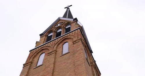 Bela igreja de tijolos altos com cruz no topo e nuvens nubladas no céu