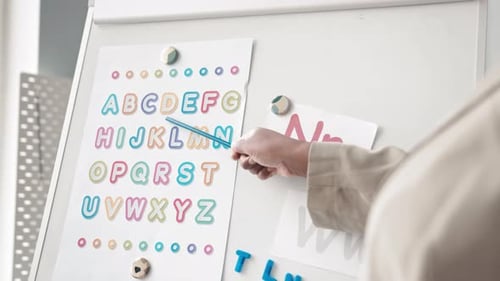Woman Teaching Alphabet with Pointer in Classroom