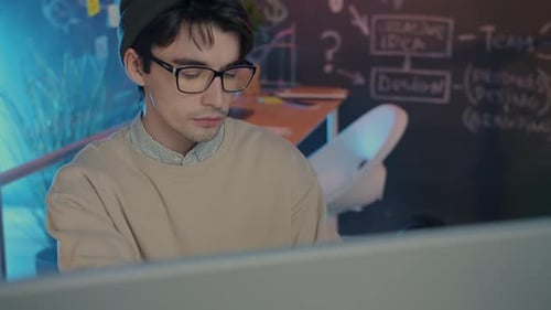 Nachdenklicher Geschäftsmann liest Dokumente und schaut auf den Computerbildschirm im dunklen Büro