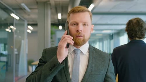 Businessman Walking in Office and Talking on Phone