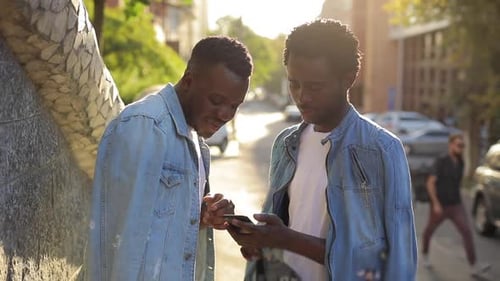 Young Adults Using Smartphone Together in City