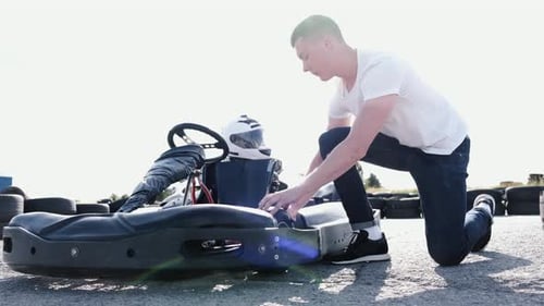 Hombre atractivo comprobando la presión de los neumáticos en su Gocart