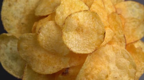 Craft crispy potato chips rotating close up. Golden fried potatoes in macro. Potato snack