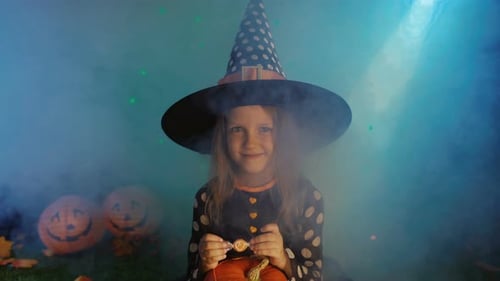 Cute Child in Witch Costume with Halloween Pumpkin