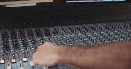 Sound engineer working in a recording studio with a sound console and microphones