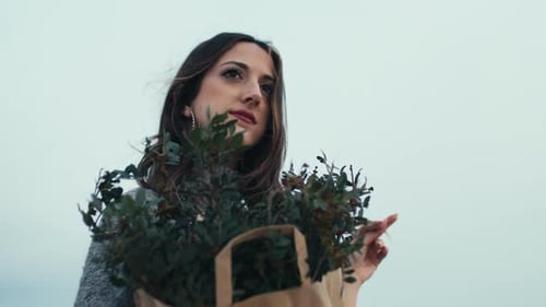 Muchacha hermosa joven con un montón de ramas en la bolsa sonríe