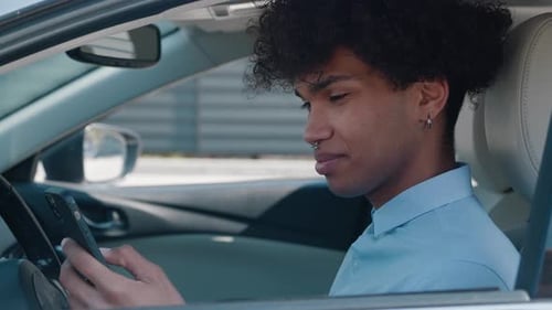 Smiling Young Adult Using Phone in Car