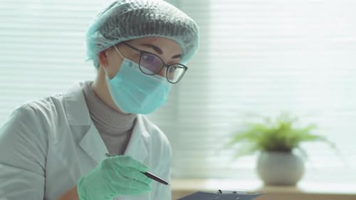 Female Doctor in Protective Mask Talking with Elderly Woman in Hospital