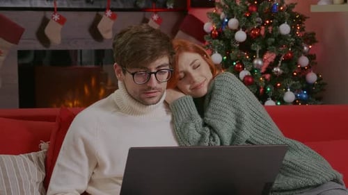 Couple Watching Laptop by Christmas Tree Fireplace