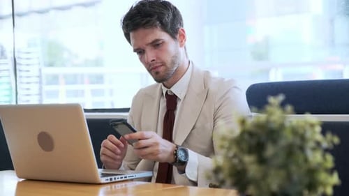 Businessman using laptop and smartphone in cafe