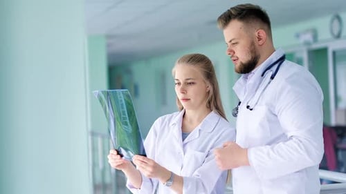 Doctors Reviewing X-Ray in Hospital Hallway