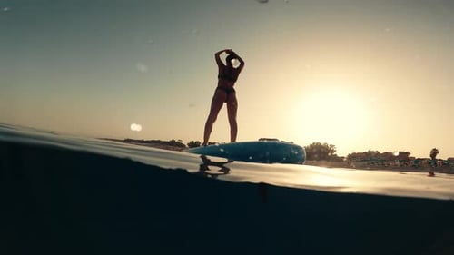 Woman Stretching on Paddle Board in Golden Light