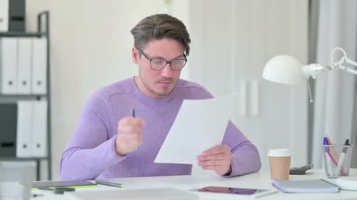 Man Reviewing Documents at Office Desk