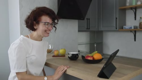 Woman Chatting on Tablet in Bright Kitchen