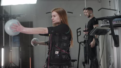 Woman Training with EMS Suit and Exercise Ball