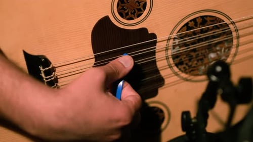 Hand plucks strings of traditional Oud instrument