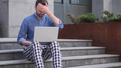 Man Frustrated Using Laptop on Urban Steps