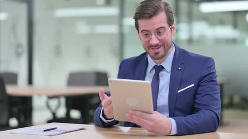 Professional Man Video Calling on Tablet in Modern Office