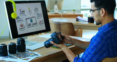 Young Adult Photographer Reviews Photos at Desk