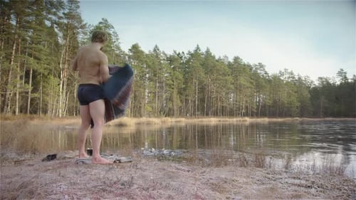 Un baigneur de glace musclé en forme res son poncho et se prépare à entrer dans le lac gelé