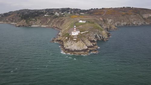 Faro de Baily en la península de Howth Head con el mar azul en primer plano en Dublín, Irlanda. - aerial pu