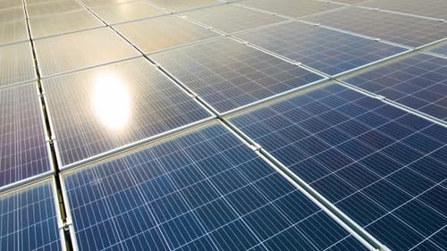 Aerial view of surface of blue photovoltaic solar panels mounted on building roof for producing