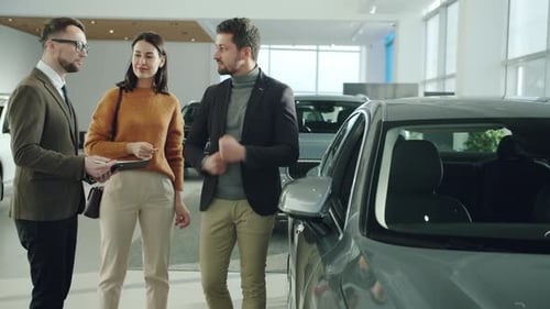 Cheerful Husband and Wife Purchasing Vehicle in Car Dealership Talking To Manager