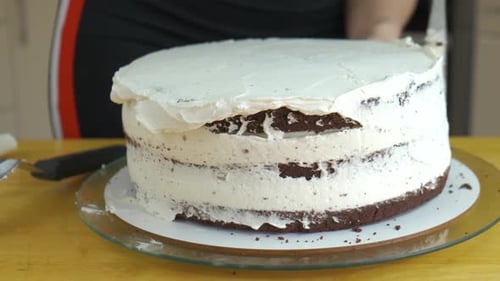 Close up of woman hands making sweet cake with white cream and biscuit.
