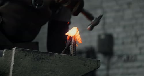 Blacksmith Strikes Glowing Metal on Anvil with Hammer