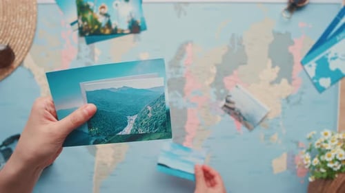 Hands Placing Travel Photos on World Map