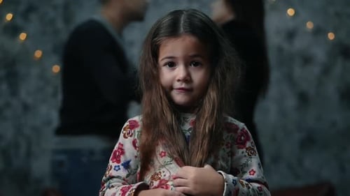 Petite fille triste regardant la caméra, ses parents se querellent sur les antécédents, les problèmes et la violence
