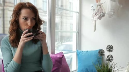 Woman Enjoying a Warm Drink in Cafe Window Seat