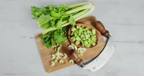 El apio picado en una tabla de cortar de madera en el plato gira lentamente.