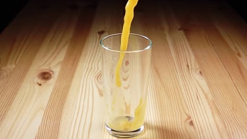 Orange Juice Being Poured into Glass on Table