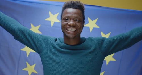 Young Man Smiling and Holding European Union Flag