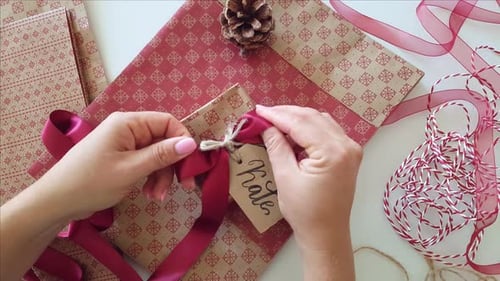 Hands Tie Ribbon on Wrapped Christmas Gift