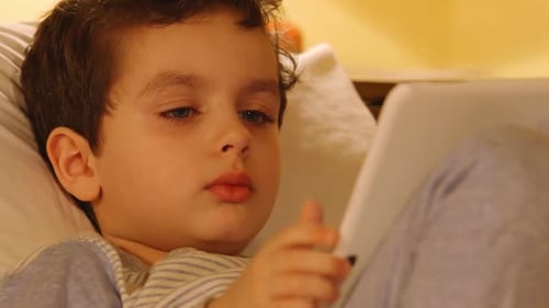 Face Of A Cute Little Boy With A White Tablet Pc At Home