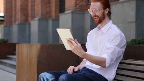 Online Video Chat on Tablet By Designer Sitting on Bench